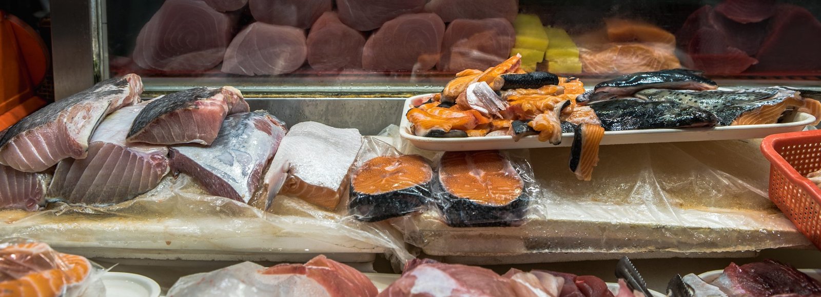 Closeup of fresh raw fishes on table in asian stall for sale. Traditional taiwanese shop of market selling a tuna and salmon. Popular marketplace of Taiwan. Sale fish food for home or restaurants.